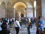 Venus stands alone at the end of a long hallway.  She is swamped with visitors.