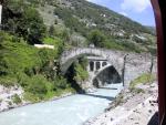 Leaving Zermatt by train - view of a glacier-fed river and ancient stone bridge.